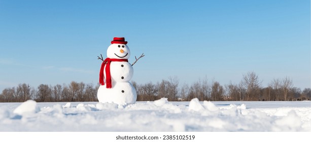 An amusing snowman, adorned with a trendy red hat and red scarf, graces a snow-covered field with a backdrop of brilliant blue skies. Christmas postcard - Powered by Shutterstock