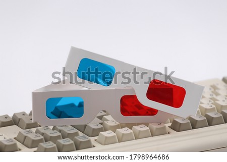 Anaglyph 3D glasses on old pc keyboard. White background. Retro Attributes 80s