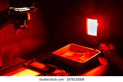 Analog photo printing. The photographer prints a black and white photograph. Photolaboratory. Red light