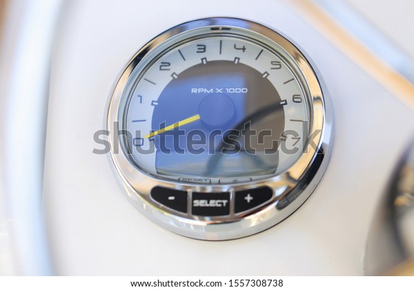 Analog tachometer on the white dashboard control\
panel of the motor boat