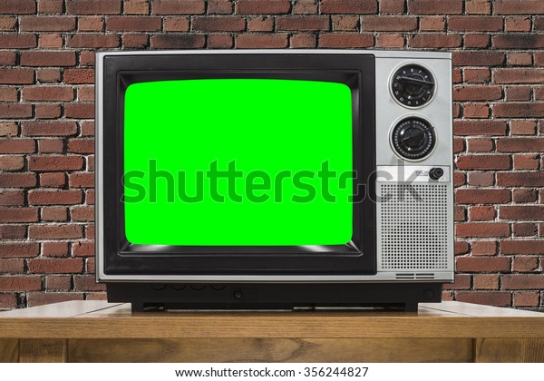 Analog television with brick wall and chroma key\
green screen.