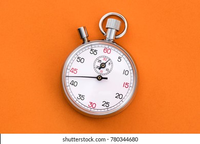 Analogue metal stopwatch on the orange background.