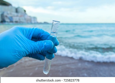 Analysis Of A Sample Of Water From A River Or Sea, Ocean. The Scientist In The Glove Took Water In A Test Tube.