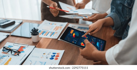 Analyst team utilizing BI Fintech to analyze financial report with tablet over paper on table and analyzing BI power dashboard display on tablet screen for business insight. Panorama shot. Scrutinize - Powered by Shutterstock