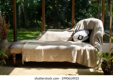 Analytical couch positioned against an open window overlooking a garden, used by psychotherapist treating patient with mental illness. 