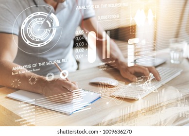 Analyze the information. Close up of professional programmer sitting at the table and making notes while coding