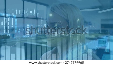 Analyzing analyst wearing light blouse studying market data at office, with candlestick charts. Woman, professional, blonde, workspace, finance, graphics, graphs