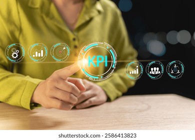Analyzing KPI indicators by using her index finger to touch an icon. Virtual icons on the screen are superimposed in front of the pointing-finger Businesswoman and an orange light is added