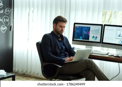 Analyzing statistical data. Side view of a young concentrated businessman, financial analyst or sales manager sitting at his workplace in the office and working on laptop. Business, finance, sales