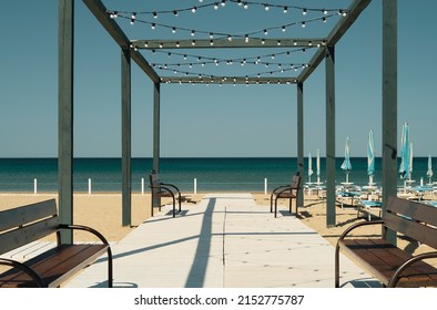 Anapa, Krasnodar Reg, Russia - April 29, 2022: Wooden Flooring, Road On The Sea, Umbrellas And Sunbeds On The Sandy Beach In The Resort Town, Sunny Day. Beach Holiday Idea