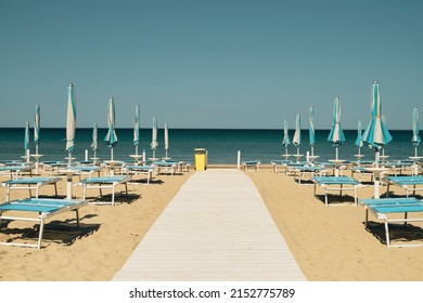 Anapa, Krasnodar Reg, Russia - April 29, 2022: Wooden Flooring, Road On The Sea, Umbrellas And Sunbeds On The Sandy Beach In The Resort Town, Sunny Day. Beach Holiday Idea