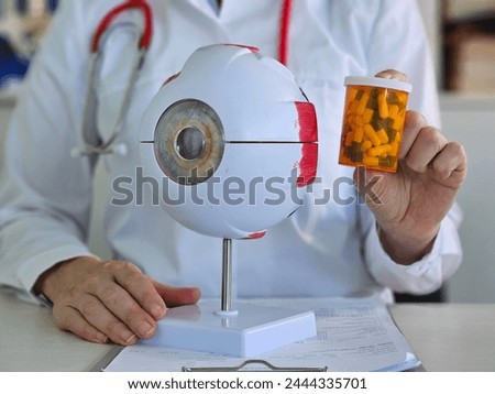 Anatomical model of eye and pills in hands of doctor. Drugs to improve vision