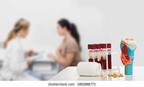 Anatomical Model Of Thyroid Gland And Blood In Test Tubes For The Analysis Of Hormones On Doctor's Table, Close-up. Endocrinologist Consulting A Patient With Endocrinological Disease