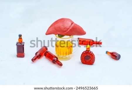 Anatomically correct clay liver model with a glass of beer and surrounding alcohol bottles. Liver functions and alcohol-related damage concept.