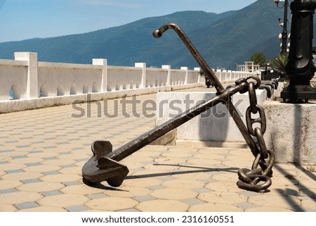Anchor with a chain on the embankment against the backdrop of the mountains