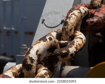 Anchor chain from a anchor winch on deck. The anchor is still inside the ship. Typical maritime background. - Shutterstock ID 2258031093