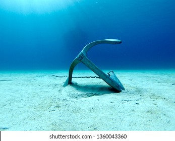 an anchor lying on the sand in the crystal blue water of the Mediterranean off the coast of minorca. 