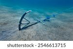 Anchor on the seabed. A metal anchor lies on the sandy seabed, buried in the ground.