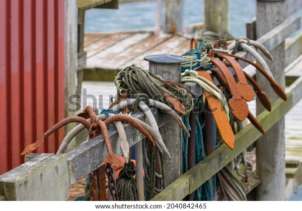 Anchor ropes and fishing tools hanging on the\
fence of a wooden bridge