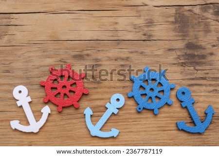 Anchor and ship wheel figures on wooden table, flat lay. Space for text