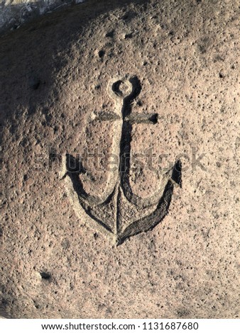 Anchor sign. A sea sign engraved on a stone. Anchor on the granite