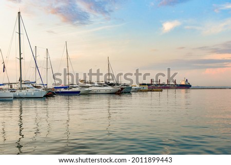 Anchorage with sailing yachts on the sea in the yacht club against the backdrop of the evening sky and sunny sunset.