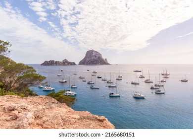 Anchored catamarans and sailing yachts in bay Cola d'Hort against backdrop of two lovely rocky islands Es Vedra and Es Vedranell. Ibiza, Balearic Islands, Spain
