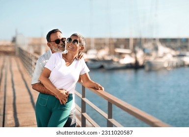 Anchored in Happiness. Joyful Mature Spouses In Love Hugging Standing Near Yachts At Sea Marina Outdoor, Wearing Summer Clothes And Sunglasses. Loving Couple Enjoying Retirement, Summer Travel - Powered by Shutterstock