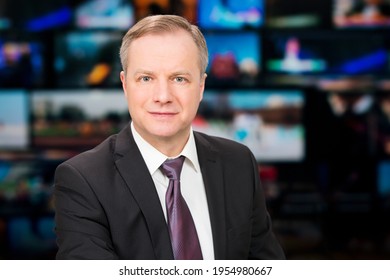 An Anchorman Reporting Live Breaking News Sitting In Tv Studio. Background Of Multiple Screens Of Broadcast Control Room. Journalism Concept