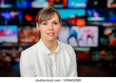 An Anchorwoman Reporting Live Breaking News Sitting In Tv Studio. Background Of Multiple Screens Of Broadcast Control Room. Journalism Concept