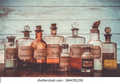 Ancient Apothecary Jars With Ingredients In French For Medicine Isolated Over White Wooden Background. Translation : Terpine Powder, Drosera And Aubepine Tincture, Kola Tincture, Iris Essential Oil