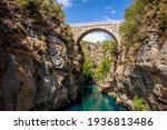 Ancient arch bridge Oluk over the Koprucay river gorge in Koprulu national Park in Turkey. Panoramic scenic view of the canyon and blue stormy mountain river