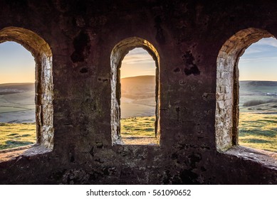 Ancient arch windows in a castle with scenic hills at sunset