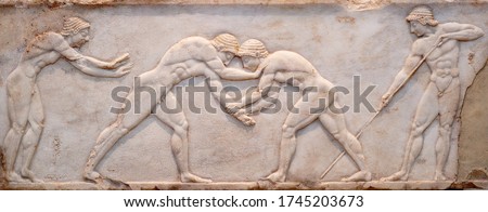 Ancient bas-relief on grave stele in Kerameikos with scene from Palaestra - wrestlers in action. On the left an athlete is ready to jump, on the right another one prepairing the pit. Athens, Greece