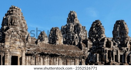The ancient Bayon Temple in Cambodia, featuring stone towers with human faces, under the sunlit sky.