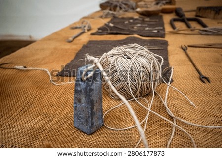 Ancient building tools featuring a lead weight and twine representing historical construction, planning, and precision craftsmanship.