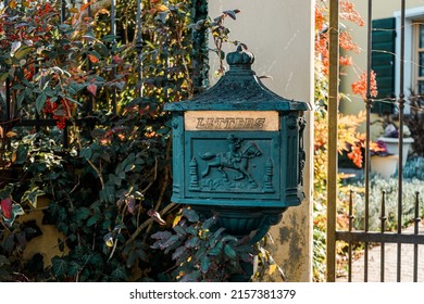 An ancient cast iron mailbox standing on a sidewalk with the word letters carved on it