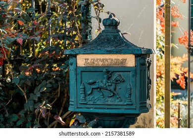 An ancient cast iron mailbox standing on a sidewalk with the word letters carved on it