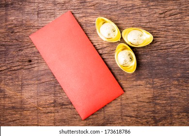 Ancient Chinese Golden Ingots And Red Pocket On Wooden Table