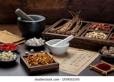 Ancient Chinese medicine books and herbs on the table.English Translation:Traditional Chinese medicine is used in the prevention and treatment of diseases, has the function of rehabilitation. - Shutterstock ID 1939053193