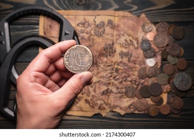 Ancient coin in treasure hunter hand close up on the metal detector, ancient coins and old treasure map background. Treasure hunting concept. - Shutterstock ID 2174300407