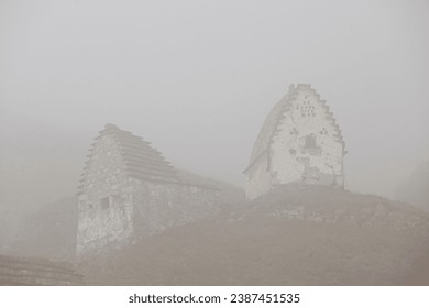 Ancient crypt for the burial of the dead. Medieval architecture in the abandoned city. A small stone house with an unusual architecture on the background of a misty sky in the mountains.