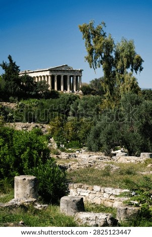 The ancient Doric Temple of Hephaestus surrounded by lush green trees in Athens, Greece.
