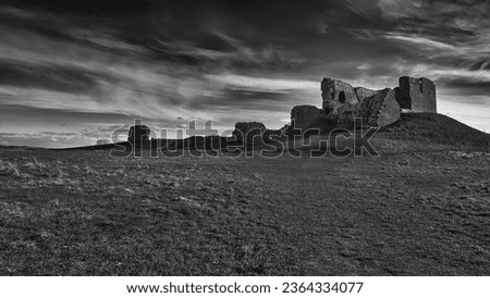 The ancient Duffus castle ruins atop a rocky hill, surrounded by clouds and overcast skies