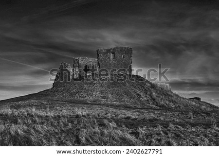 The ancient Duffus castle ruins atop a rocky hill, surrounded by clouds and overcast skies