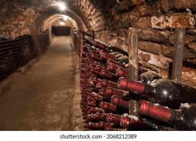 Ancient Dusty Wine Bottles In An Old Cellar. Expensive Wine In The Historic Cellar. Old Wine Bottles In Rows In The Wine Cellar.