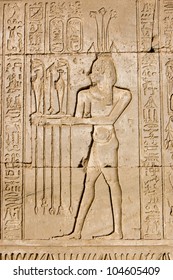 Ancient Egyptian Hieroglyphic Carving Of A Priest Making An Offering To Hapi, The God Of The Nile.  Shown By The Lotus On His Head.  Outer Wall Of Dendera Temple, Near Qena, Egypt.