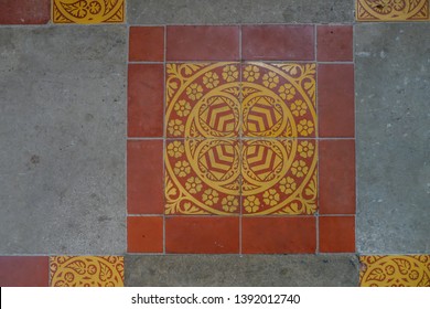 Ancient English Floor Tile Closeup.  Beautiful Traditional Patterns In Yellow And Red Surrounded By Cement.  Patterns Of Shields And English Rose In Perfect Symetry.