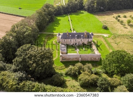 An ancient French castle with a courtyard among fields, filmed from a bird's eye view using a drone.