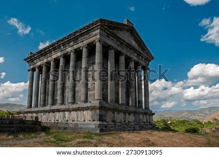 Ancient Garni temple complex built by King Tiridates I in the first century AD. Garni, Kotayk Province, Armenia. Low angle perspective view, cloudy blue sky